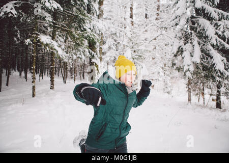 Ein Teenager läuft in einem Winter Wald voller tiefen Schnee. Stockfoto