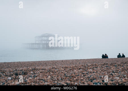 Leute sitzen auf den Strand an der West Pier in Brighton, der beliebteste Badeort in Großbritannien für ausländische Touristen. Stockfoto