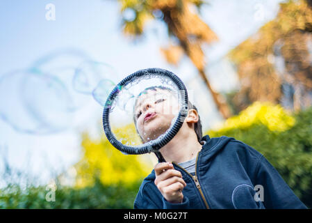 7-jährige Kind im Garten im Winter macht grosse Seifenblasen Stockfoto