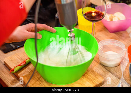Close up Frau Schlagsahne Eier mit Mixer in grün Kunststoff Schüssel Stockfoto