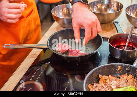 Nahaufnahme, Hände von Chef, rohes Fleisch in Pfanne beim Kochen workshop Stockfoto