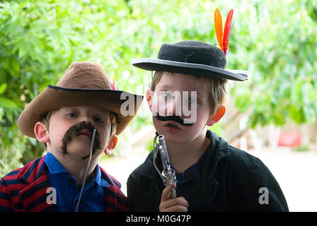 Nahaufnahme Portrait von fünf jährige Zwillingsbrüder als Cowboys auf der Suche direkt in die Kamera mit Garten im Hintergrund gekleidet Stockfoto