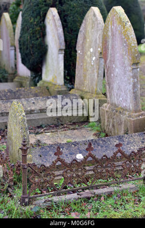 Gräber und Grabsteine auf einem Friedhof mit Grabsteinen und bemoosten Flechten wachsen auf dem Mauerwerk. Memorial Maurer Arbeit mit Skulpturen aus Stein Inschriften Stockfoto