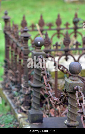 Eine geheimnisvolle, Moody und stimmungsvolle Bild von einigen alten Viktorianischen gusseisernen Geländer rund um den Rand eines Grabes oder Grab auf einem Friedhof oder Friedhof. Stockfoto