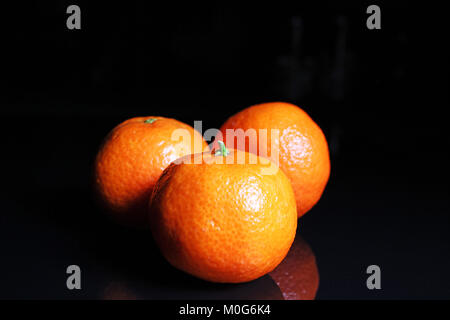 Mandarinen. Mandarine Citrus orange Obst Mandarinen auf Schwarz reflektierende studio Hintergrund. Isolierte schwarze glänzende Spiegel gespiegelt Hintergrund für jede con Stockfoto