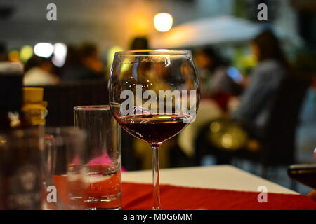 Ein halb leeres Glas Wein sitzt auf der Tabelle der ein Straßencafe in Split Kroatien Stockfoto