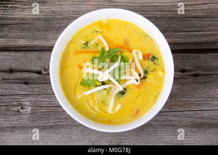 Leckere Thai curry Coconut chiken Soup Bowl über rustikale plank Hintergrund Stockfoto