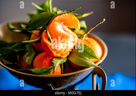 Eine Nahaufnahme eines frischen saftigen Clementinen mit grünen Blättern im Maßstab Schüssel Stockfoto