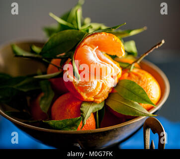 Eine Nahaufnahme eines frischen saftigen Clementinen mit grünen Blättern im Maßstab Schüssel Stockfoto