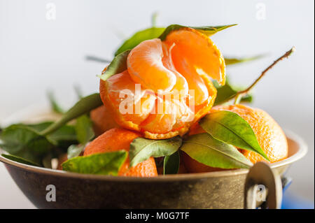 Eine Nahaufnahme eines frischen saftigen Clementinen mit grünen Blättern im Maßstab Schüssel Stockfoto