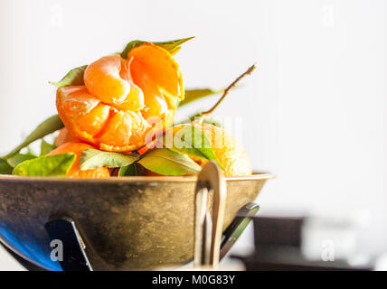 Eine Nahaufnahme eines frischen saftigen Clementinen mit grünen Blättern im Maßstab Schüssel Stockfoto