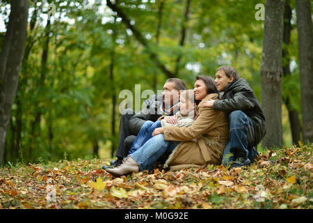Glücklich lächelnde Familie sitzt auf den Blättern
