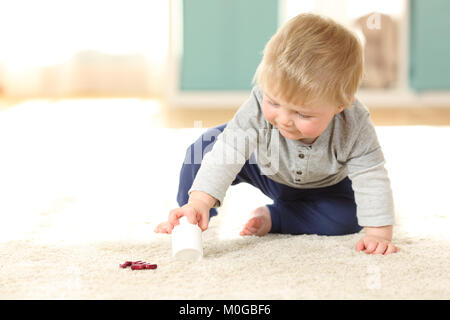 Baby in Gefahr spielen mit einer Flasche Pillen auf dem Boden zu Hause Stockfoto