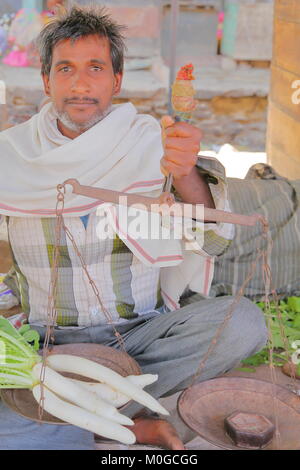 BUNDI, Rajasthan, Indien - Dezember 08, 2017: Portrait eines Verkäufers Holding eine herkömmliche Waage am Gemüsemarkt Stockfoto