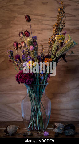 Noch immer leben von getrockneten Blumen im Glas Container auf Holztisch mit roßkastanie und Acorn Samen gegen Holz Wand Hintergrund eingerichtet Stockfoto