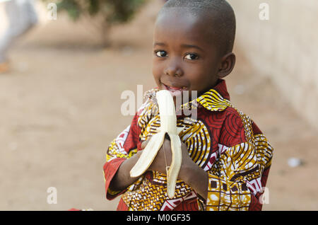 Candid Shot der Afrikanischen schwarzen Jungen essen Banana Outdoor Stockfoto