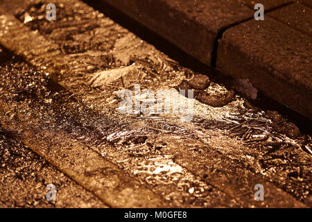 Vereisung auf Wasser in der Gosse auf der Straße mit einem gelben Linien in der Nacht in der Uk Stockfoto