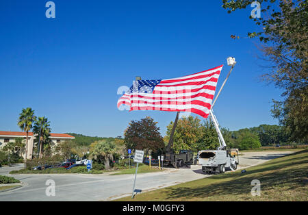 Riesige amerikanische Flagge Wellen in der Brise von hohen Eimer Nutzfahrzeuge in der Feier des Veterans Day. Stockfoto