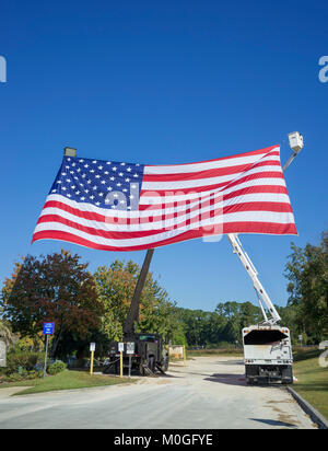 Riesige amerikanische Flagge Wellen in der Brise von hohen Eimer Nutzfahrzeuge in der Feier des Veterans Day. Stockfoto