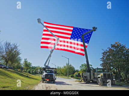 Riesige amerikanische Flagge Wellen in der Brise von hohen Eimer Nutzfahrzeuge in der Feier des Veterans Day. Stockfoto