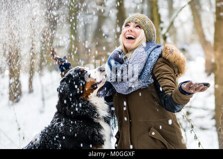 Frau zu ihrem Hund im Winter und den Schnee zu erkunden Stockfoto