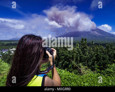 Camalig, Albay, Philippinen. 22 Jan, 2018. Eine Frau nimmt Bilder von einem Ausbruch des Mayon Vulkan. Es gab eine Reihe von Eruptionen auf der Mayon Vulkan in der Nähe von Legazpi Montag. Die Eruptionen begann Sonntag Nacht und weiter durch den Tag. Um ca. 12.00 Uhr den Vulkan gesendet eine Wolke aus Asche und Rauch hoch über Camalig, die größte Gemeinde in der Nähe des Vulkans. Credit: ZUMA Press, Inc./Alamy leben Nachrichten Stockfoto