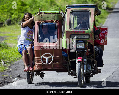 Camalig, Albay, Philippinen. 22 Jan, 2018. Die Menschen fahren mit dem Philippinischen Dreirad Taxi, während sie ihre Gemeinschaften an den Hängen des Mayon Vulkan verlassen. Es gab eine Reihe von Eruptionen auf der Mayon Vulkan in der Nähe von Legazpi Montag. Die Eruptionen begann Sonntag Nacht und weiter durch den Tag. Um ca. 12.00 Uhr den Vulkan gesendet eine Wolke aus Asche und Rauch hoch über Camalig, die größte Gemeinde in der Nähe des Vulkans. Credit: ZUMA Press, Inc./Alamy leben Nachrichten Stockfoto