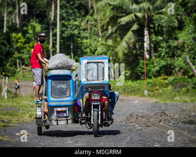 Camalig, Albay, Philippinen. 22 Jan, 2018. Die Menschen fahren mit dem Philippinischen Dreirad Taxi, während sie ihre Gemeinschaften an den Hängen des Mayon Vulkan verlassen. Es gab eine Reihe von Eruptionen auf der Mayon Vulkan in der Nähe von Legazpi Montag. Die Eruptionen begann Sonntag Nacht und weiter durch den Tag. Um ca. 12.00 Uhr den Vulkan gesendet eine Wolke aus Asche und Rauch hoch über Camalig, die größte Gemeinde in der Nähe des Vulkans. Credit: ZUMA Press, Inc./Alamy leben Nachrichten Stockfoto