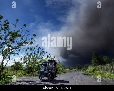 Camalig, Albay, Philippinen. 22 Jan, 2018. Die Menschen fahren mit dem Philippinischen Dreirad Taxi, während sie ihre Gemeinschaften an den Hängen des Mayon Vulkan verlassen. Es gab eine Reihe von Eruptionen auf der Mayon Vulkan in der Nähe von Legazpi Montag. Die Eruptionen begann Sonntag Nacht und weiter durch den Tag. Um ca. 12.00 Uhr den Vulkan gesendet eine Wolke aus Asche und Rauch hoch über Camalig, die größte Gemeinde in der Nähe des Vulkans. Credit: ZUMA Press, Inc./Alamy leben Nachrichten Stockfoto