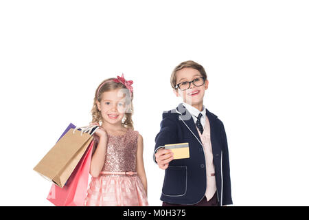 Schöne stilvolle Kinder mit Einkaufstüten und Kreditkarte bei Kamera lächelnd isoliert auf weißem Stockfoto