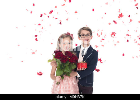 Adorable happy Kids mit Rosen und Herzförmigen Geschenkbox umarmen und lächelnd an der Kamera auf Weiß Stockfoto