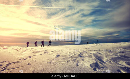 Winter Berglandschaft mit Reisende Silhouetten bei Sonnenuntergang, Farbe getonte Bild. Stockfoto