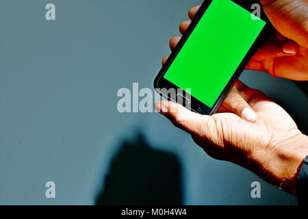 Grüner Bildschirm Bereit Android und mann Betrachtung gegen gestreifte Fenster von Schatten und Licht Muster Stockfoto