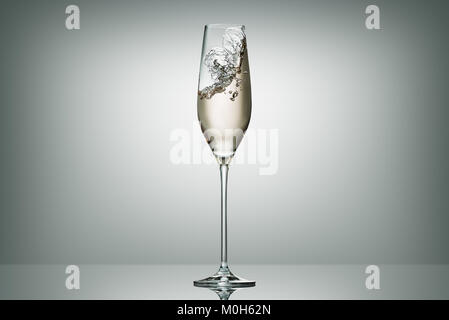 Spritzer Champagner in transparentem Glas auf Weiß Stockfoto