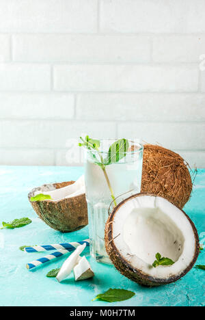 Gesunde Ernährung Konzept. Frische organische Kokosnuss Wasser mit Kokosnüssen, Eiswürfel und Minze, auf hellblauem Hintergrund, kopieren Raum Stockfoto