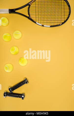 Schwarz Kurzhanteln und Tennisschläger mit Kugeln isoliert auf Gelb Stockfoto