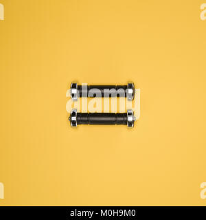 Schwarz glänzend Kurzhanteln auf gelbem Hintergrund Stockfoto