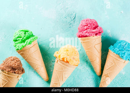 Auswahl von verschiedenen hellen bunten Eis in Eistüten - Schoko Vanille Erdbeere Heidelbeere Pistazie orange, hellblau Sunny b Stockfoto
