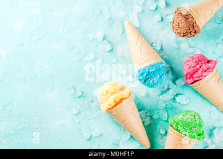 Auswahl von verschiedenen hellen bunten Eis in Eistüten - Schoko Vanille Erdbeere Heidelbeere Pistazie orange, hellblau Sunny b Stockfoto