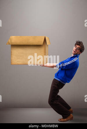 Gut aussehende junge Mann mit einem leeren braunen Karton Stockfoto