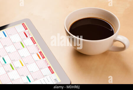 Arbeitsplatz mit tablet pc, Kalender und eine Tasse Kaffee auf einer hölzernen Arbeitstisch close-up Stockfoto