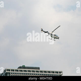 Die agusta-bell AB 206B Jet Ranger III N 408 HERR Hubschrauber über den 1 New York Plaza Gebäude fliegen gegen den bewölkten Himmel, im südlichen Manhattan, New Y Stockfoto