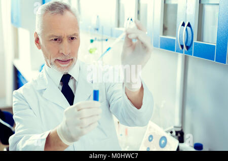 Konzentrierte sich Forscher mit Pipette, die während der Arbeit mit chemischen Flüssigkeiten Stockfoto