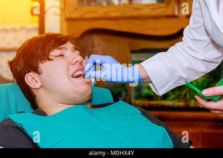 Mann im Zahnarztstuhl lächelnd. Mann Mund weit geöffnet im Stuhl Mann der Zahnarzt beim Zahnarzt kieferorthopädische Silikon zahnmedizinische überprüfung Stockfoto