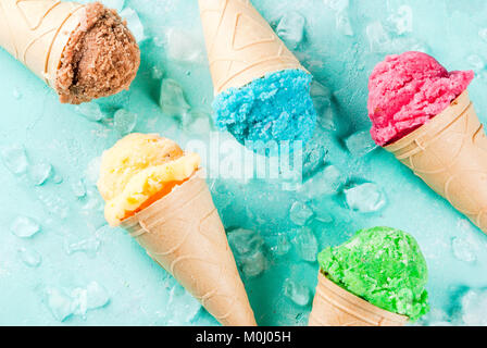 Auswahl von verschiedenen hellen bunten Eis in Eistüten - Schoko Vanille Erdbeere Heidelbeere Pistazie orange, hellblau Sunny b Stockfoto