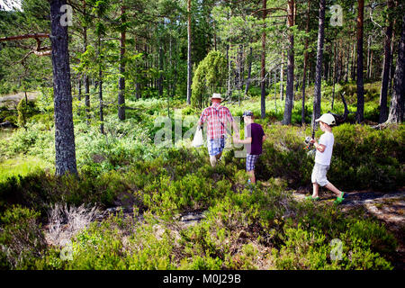 Großvater und Enkel sind zu Fuß auf einem Waldweg mit Angeln in Norwegen. Stockfoto