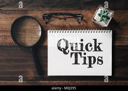 Lupe, Gläser, Kakteen und Notebook mit TIPPS Wort auf Holztisch. schnelle Tipps Konzept. Stockfoto