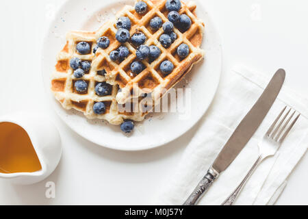 Blick von oben auf die Platte der leckere frische Waffeln mit Blaubeeren, Honig und Besteck Stockfoto