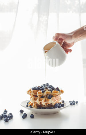 7/8 Schuß von Frau gießen köstlichen frischen Honig auf leckere Waffeln Stockfoto