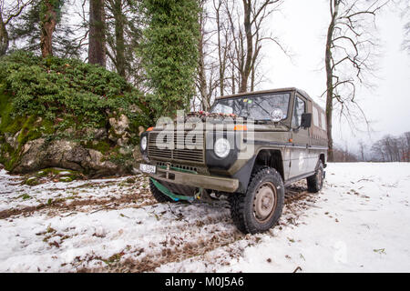 4x4 Puch Armee Fahrzeug parken vor einem Wald und Felsen in einer kalten, schneereichen Winter Tag Stockfoto